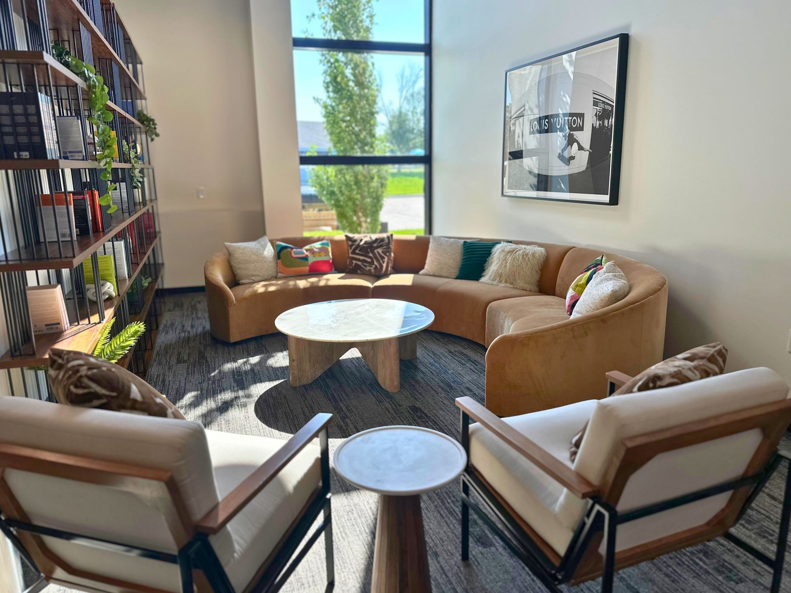Sunlit lounge with curved sofa, armchairs, and full height windows at SpringPad in Lincoln, Nebraska