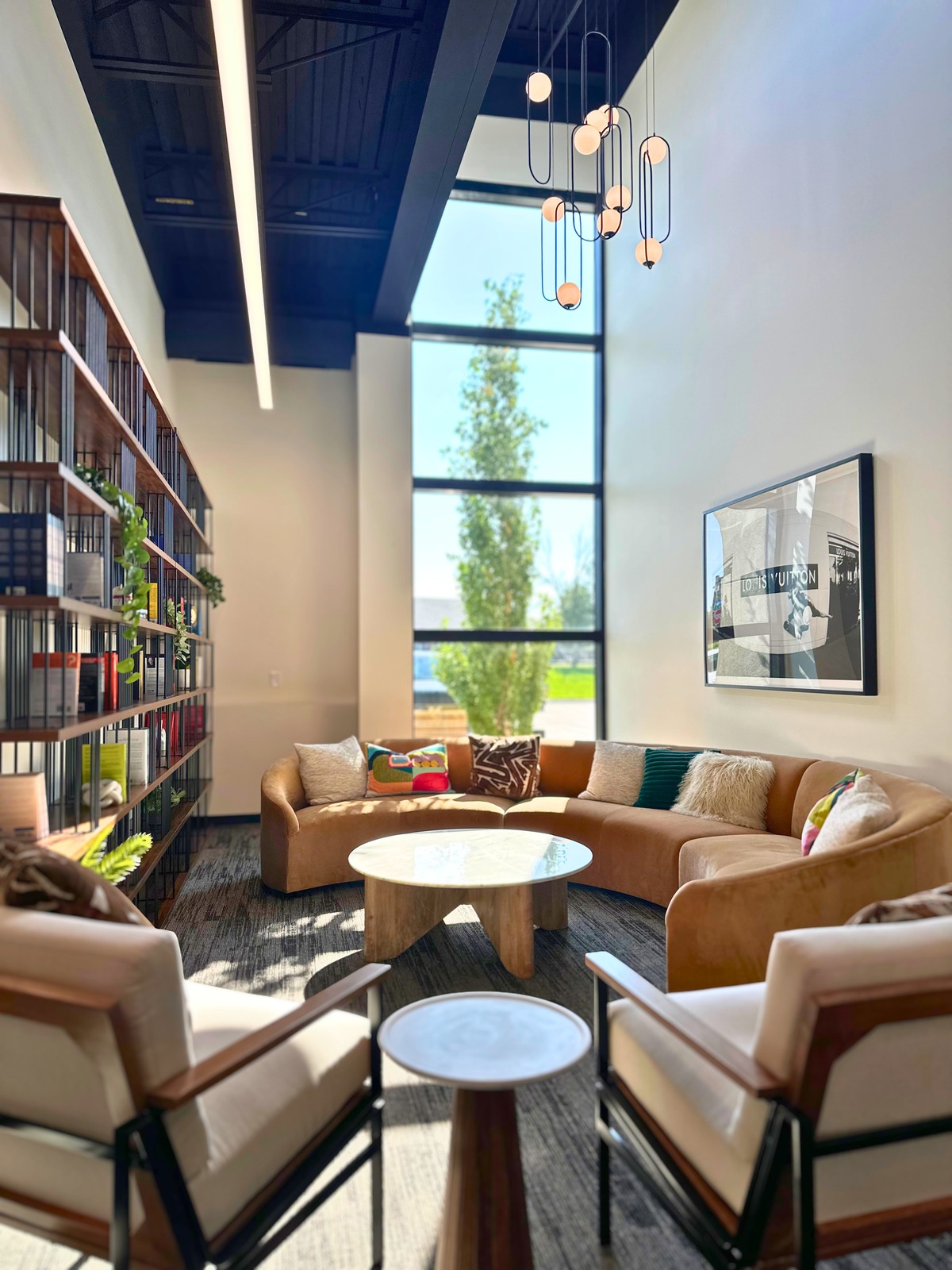 Double-height lounge with bookshelf wall and pendant lights at SpringPad in Lincoln, Nebraska